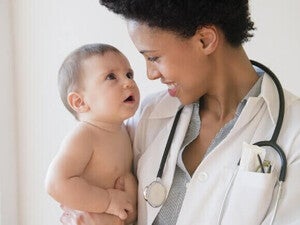 Médico sorridente segurando um bebê. Exame do bebê contra rotavírus.