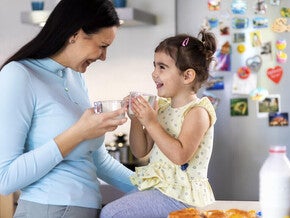 Família com uma menina compartilhando uma refeição em casa, sentada na cozinha e curtindo junta.