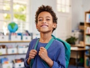 Criança com mochila sorrindo em sua nova escola