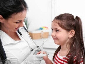 Menina com a boca aberta sendo examinada por um médico, simulando a avaliação de problemas respiratórios e de garganta relacionados à adenoide.