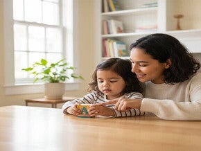 Mãe e filho brincando com blocos de letras em casa, preparando-se para a alfabetização.