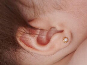 Orelha de um bebê com um brinco pequeno.