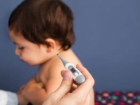 imagem de um médico aferindo a temperatura de um bebê