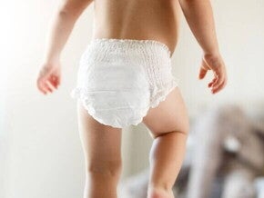 Bebê caminhando de fralda sob um fundo desfocado