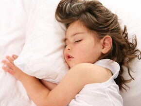 Uma criança deitada na cama e dormindo.