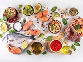 Uma vista aérea de diversos alimentos dispostos sobre uma superfície clara, organizados em tigelas de madeira, tábuas de corte e pequenos recipientes.