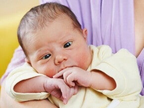 Bebê nos braços de um adulto, com aparência serena e leve desvio no olhar, sugerindo possível caso de falso estrabismo.