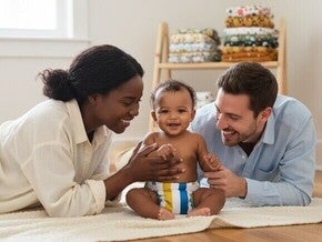 Pai e mãe sorrindo para o bebê que está usando fralda ecológica