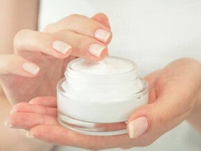 Uma pessoa adulta segurando um pote com um creme hidratante