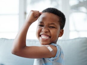 menino feliz sorri com braço levantado e um band-aid menino feliz sorri com braço levantado e um band-aid