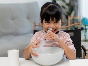 Um bebê deitado com a boca aberta, enquanto uma mão segura uma seringa próxima ao nariz do bebê Um bebê deitado com a boca aberta, enquanto uma mão segura uma seringa próxima ao nariz do bebê