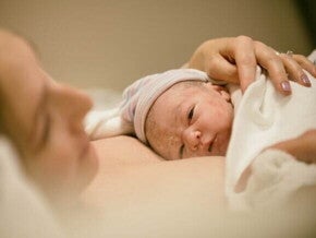 Um bebê recém-nascido deitado no colo de uma mulher.