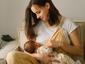mulher sentada amamentando bebê que está no seu colo
