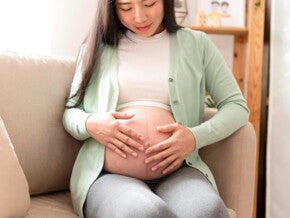 mulher sentada no sofá acaricia seu umbigo inflamado