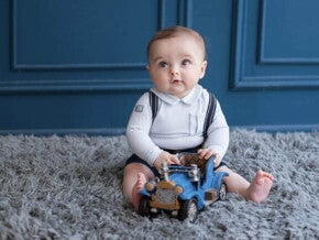 bebê menino sentado em tapete felpudo cinza, com carrinho de brinquedo azul em mãos. bebê menino sentado em tapete felpudo cinza, com carrinho de brinquedo azul em mãos.