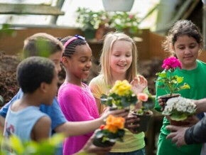 Um grupo de crianças em um jardim comunitário, segurando vasos de plantas coloridas e sorrindo enquanto participam de uma atividade de jardinagem. Um grupo de crianças em um jardim comunitário, segurando vasos de plantas coloridas e sorrindo enquanto participam de uma atividade de jardinagem.