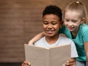 Duas crianças sorrindo, lendo um livro juntas. Duas crianças sorrindo, lendo um livro juntas.