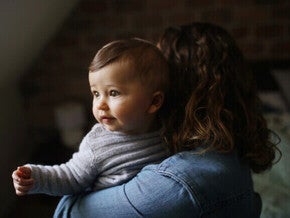 Mãe carregando um bebê de 8 meses com refluxo.