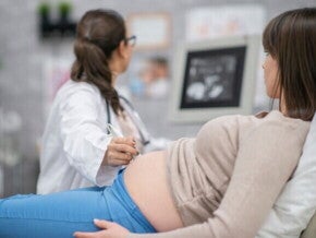 Uma mulher grávida deitada enquanto uma profissional de saúde realiza um ultrassom abdominal.