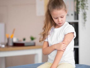 Uma criança sentada em um sofá segurando o braço