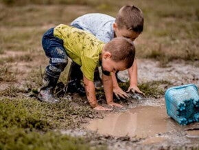 Duas crianças brincando com as mãos na lama e as roupas sujas. Duas crianças brincando com as mãos na lama e as roupas sujas.