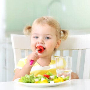 Pequeña comiendo verduras durante la comida.