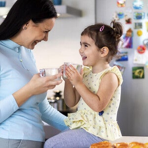 Família com uma menina compartilhando uma refeição em casa, sentada na cozinha e curtindo junta.