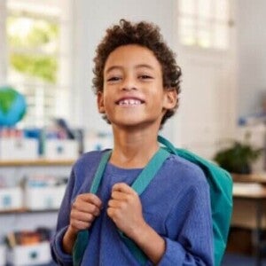 Criança com mochila sorrindo em sua nova escola
