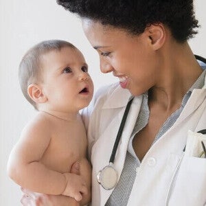 Médico sorridente segurando um bebê. Exame do bebê contra rotavírus.