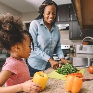 alimentos ricos em ferro Mãe e filha na cozinha preparando refeição com alimentos ricos em ferro