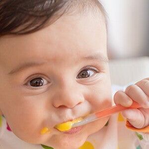 Infant grinning and eating puree. Infant grinning and eating puree.