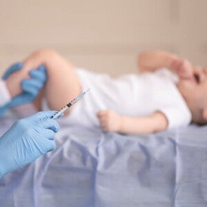 bebê deitado e enfermeira segurando uma seringa bebê deitado e enfermeira segurando uma seringa
