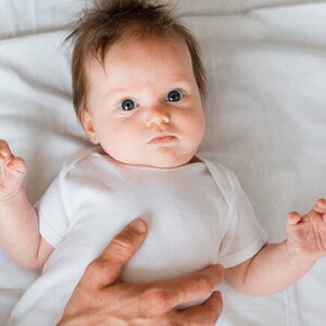 Bebê deitado em uma cama recebendo cuidados de uma profissional de saúde Bebê deitado em uma cama recebendo cuidados de uma profissional de saúde