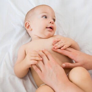 bebê usando fralda e um adulto com as mãos sob a barriga do bebê bebê usando fralda e um adulto com as mãos sob a barriga do bebê