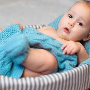 Imagem de um bebê aconchegado em um cobertor azul dentro de uma cesta Imagem de um bebê aconchegado em um cobertor azul dentro de uma cesta