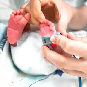 Pés de um bebê recém-nascido passando por uma avaliação pelas mão de um profissional da saúde. Pés de um bebê recém-nascido passando por uma avaliação pelas mão de um profissional da saúde.