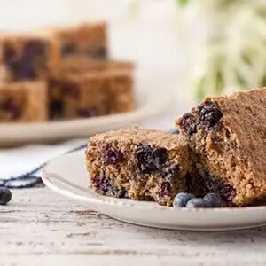 Pedaço de Bolo Integral de Banana e Blueberry, sem Açúcar e sem Lactose em um prato branco Pedaço de Bolo Integral de Banana e Blueberry, sem Açúcar e sem Lactose em um prato branco
