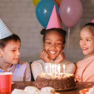 diversas crianças sorriem ao redor de bolo sobre mesa diversas crianças sorriem ao redor de bolo sobre mesa