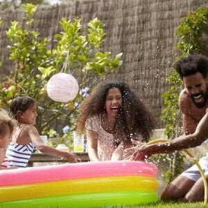 Foto de uma família se divertindo em um ambiente aberto com uma piscina de plástico colorida Foto de uma família se divertindo em um ambiente aberto com uma piscina de plástico colorida