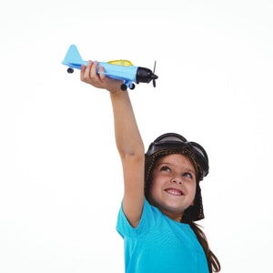Menina sorrindo e segurando um avião de brinquedo acima da sua cabeça Menina sorrindo e segurando um avião de brinquedo acima da sua cabeça