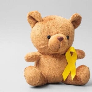 Urso de pelúcia com um laço dourado que simboliza o mês da conscientização sobre o câncer infantil Urso de pelúcia com um laço dourado que simboliza o mês da conscientização sobre o câncer infantil