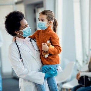 médica sorrindo enquanto segura uma criança em um ambiente hospitalar médica sorrindo enquanto segura uma criança em um ambiente hospitalar