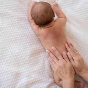 bebê com mancha mongólica nas costas deitado na cama bebê com mancha mongólica nas costas deitado na cama