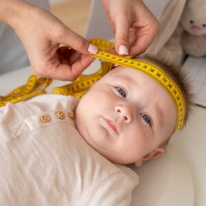 imagem de uma médica colocando uma fita métrica em torno da cabeça do bebê que está deitado imagem de uma médica colocando uma fita métrica em torno da cabeça do bebê que está deitado