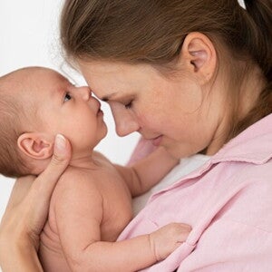 Mãe segurando a filha recém nascida no colo e com os rostos juntos. Mãe segurando a filha recém nascida no colo e com os rostos juntos.