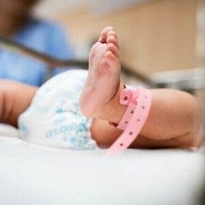 Close de um bebê recém-nascido deitado em um berço hospitalar, com uma pulseira rosa de identificação no tornozelo, simbolizando cuidados neonatais e saúde infantil. Close de um bebê recém-nascido deitado em um berço hospitalar, com uma pulseira rosa de identificação no tornozelo, simbolizando cuidados neonatais e saúde infantil.