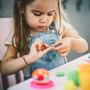 A foto mostra uma criança brincando de massinha de modelar e estimulando a coordenação motora fina A foto mostra uma criança brincando de massinha de modelar e estimulando a coordenação motora fina