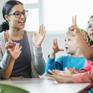 creche Imagem de uma tutora interagindo com crianças ao redor de uma mesa. Brincadeiras entre professores e crianças ajudam na adaptação na creche dos pequenos