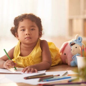 menina com blusa amarela segurando um lápis e desenhando em um caderno menina com blusa amarela segurando um lápis e desenhando em um caderno