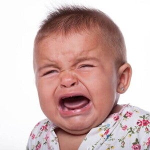 Um bebê chorando, com a boca aberta, sobre um fundo branco Um bebê chorando, com a boca aberta, sobre um fundo branco